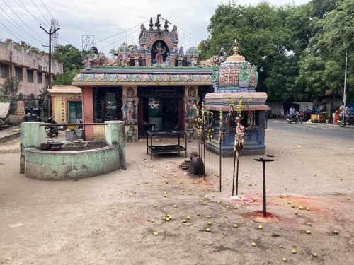 a small temple on the side of the road with lots of broken fruit outside